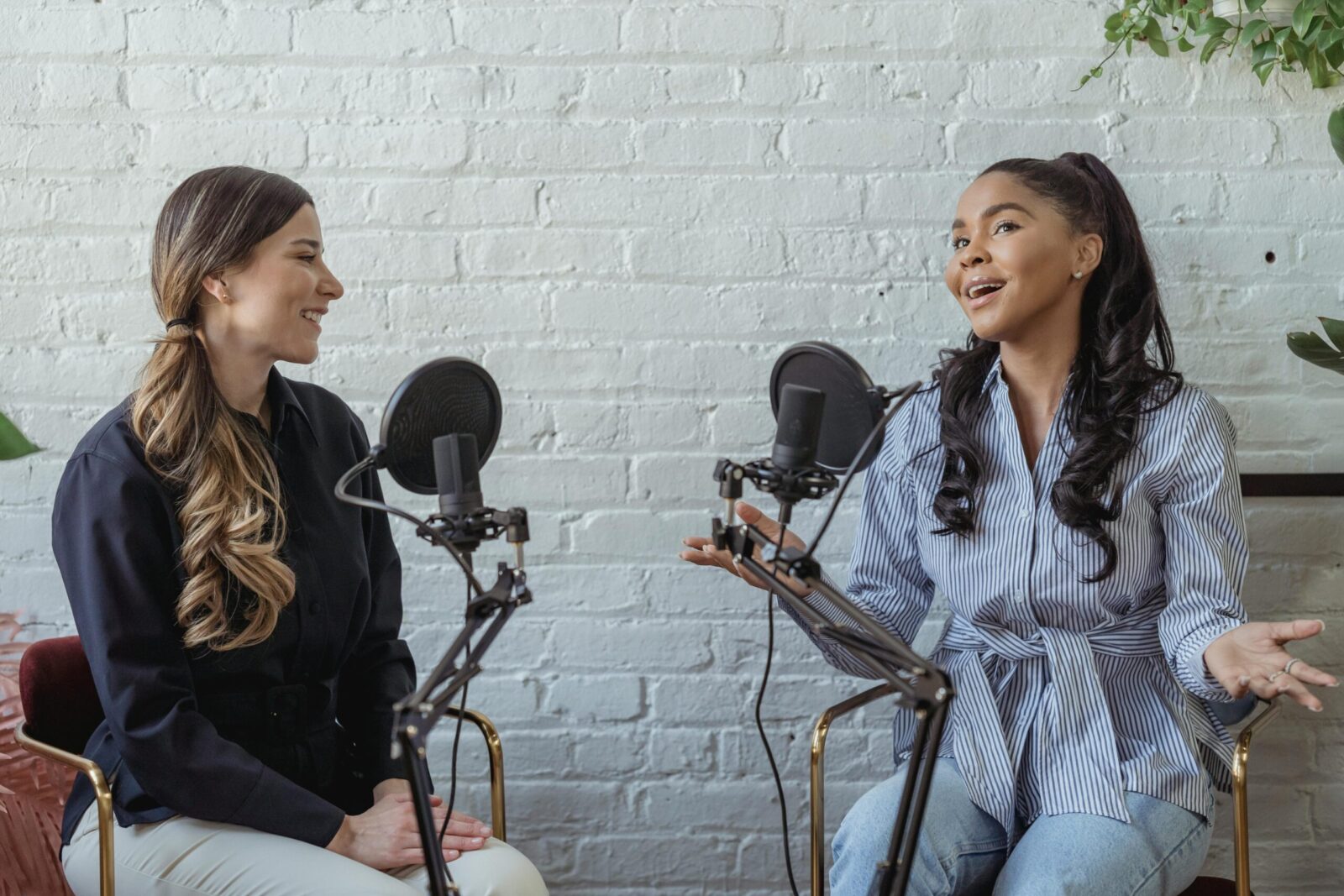 Two women recording a podcast with microphones in a studio — thumbnail for HollowBlitz Studio’s corporate podcast editing project.